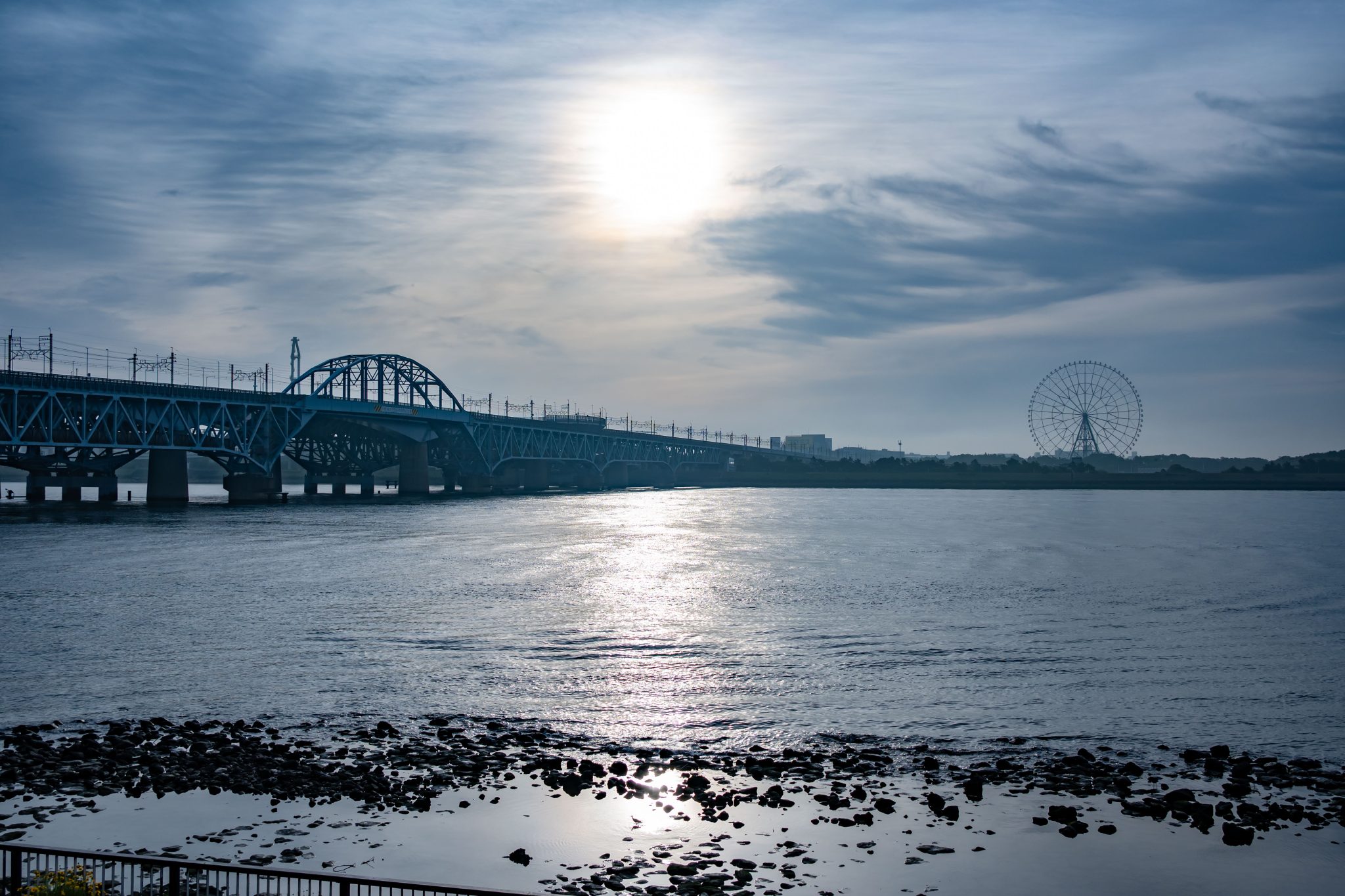 In early morning light, the sun reflects on the Arakawa River, with the JR Keiyo Line bridge and a d